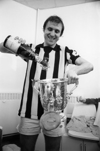 Manchester City's winning goalscorer Dennis Tueart, wearing a Newcastle United shirt, celebrates victory in the changing rooms after the match